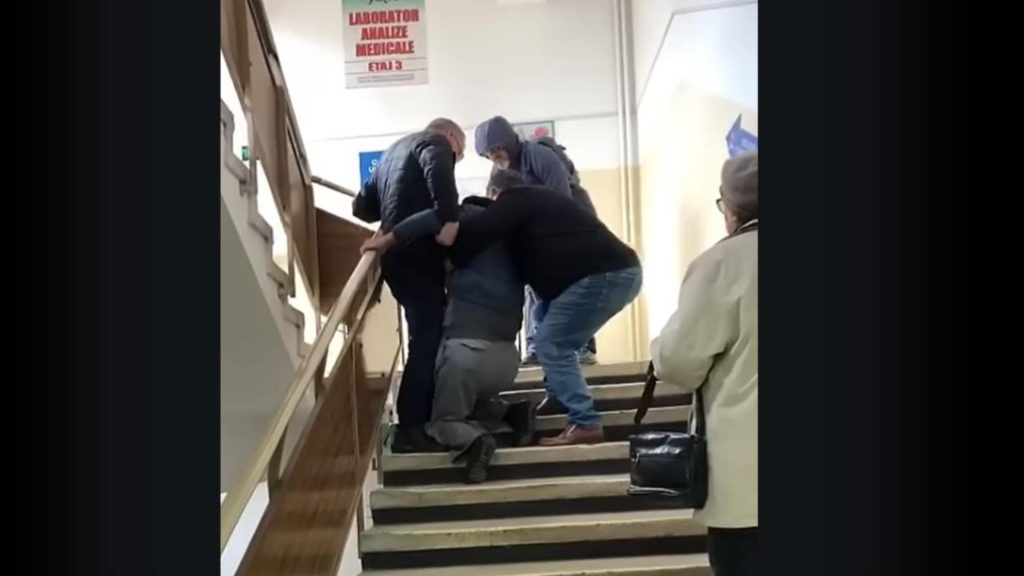 România umilită. Pacient cu probleme la picioare, târât pe scări de două persoane pentru a ajunge la cabinetul medicului VIDEO
